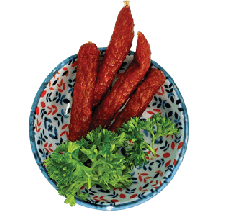 Several pieces of vegan salami are presented in a small patterned bowl with parsley.
