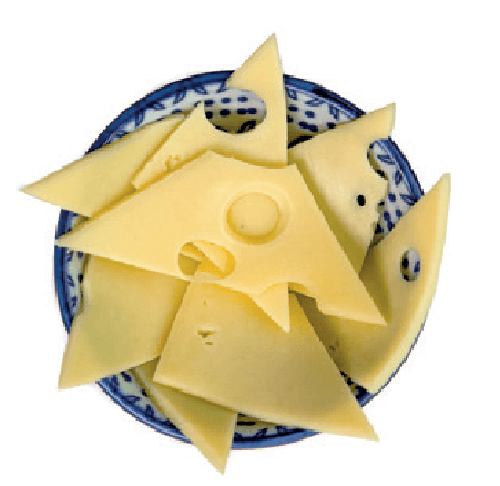 Triangular and irregular slices of emmental cheese with holes are arranged in a small patterned bowl.