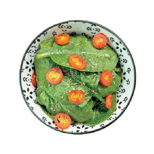 A small bowl of fresh spinach salad is topped with sliced cherry tomatoes and a sprinkle of seasoning.