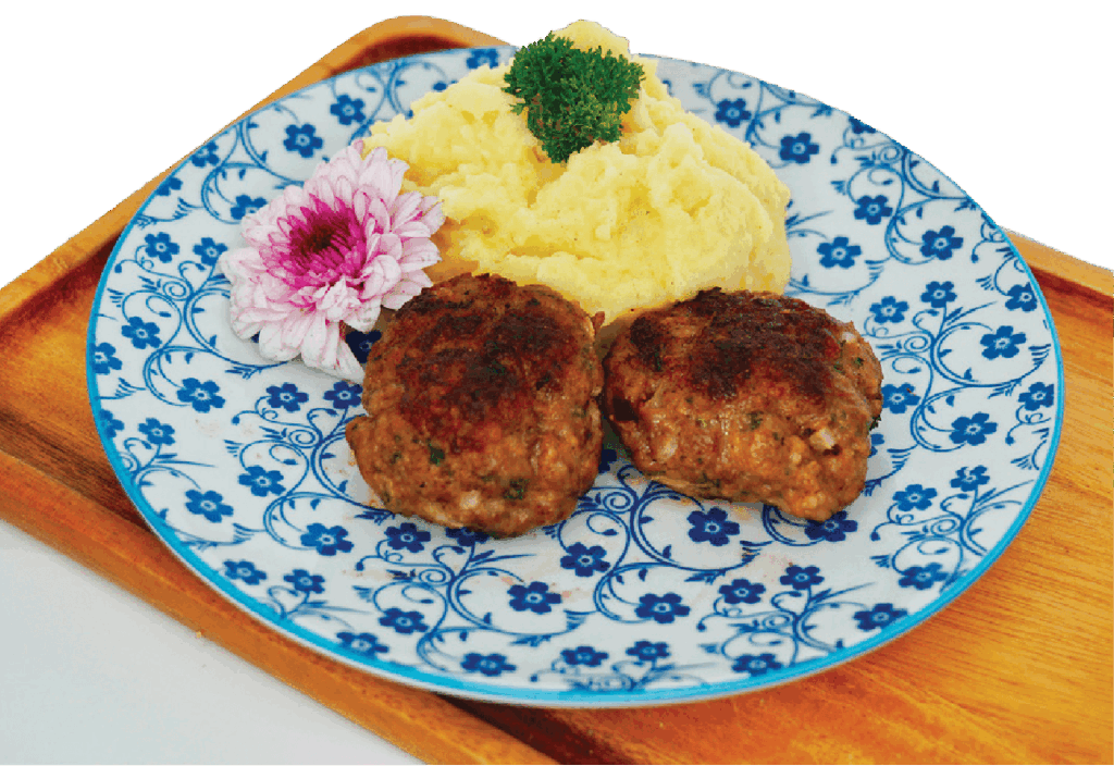 Two German-style meatballs (Frikadellen) are served with a scoop of mashed potatoes and a flower garnish on a blue patterned plate.