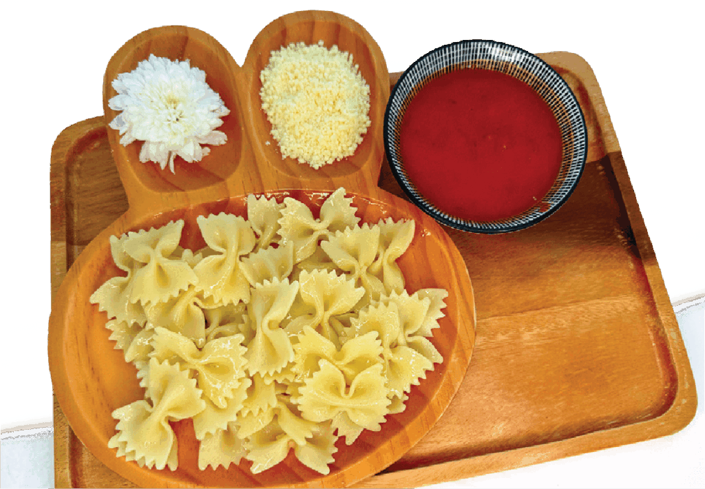 Cooked bowtie pasta, a bowl of tomato sauce, and a portion of grated parmesan cheese are arranged on a wooden tray.
