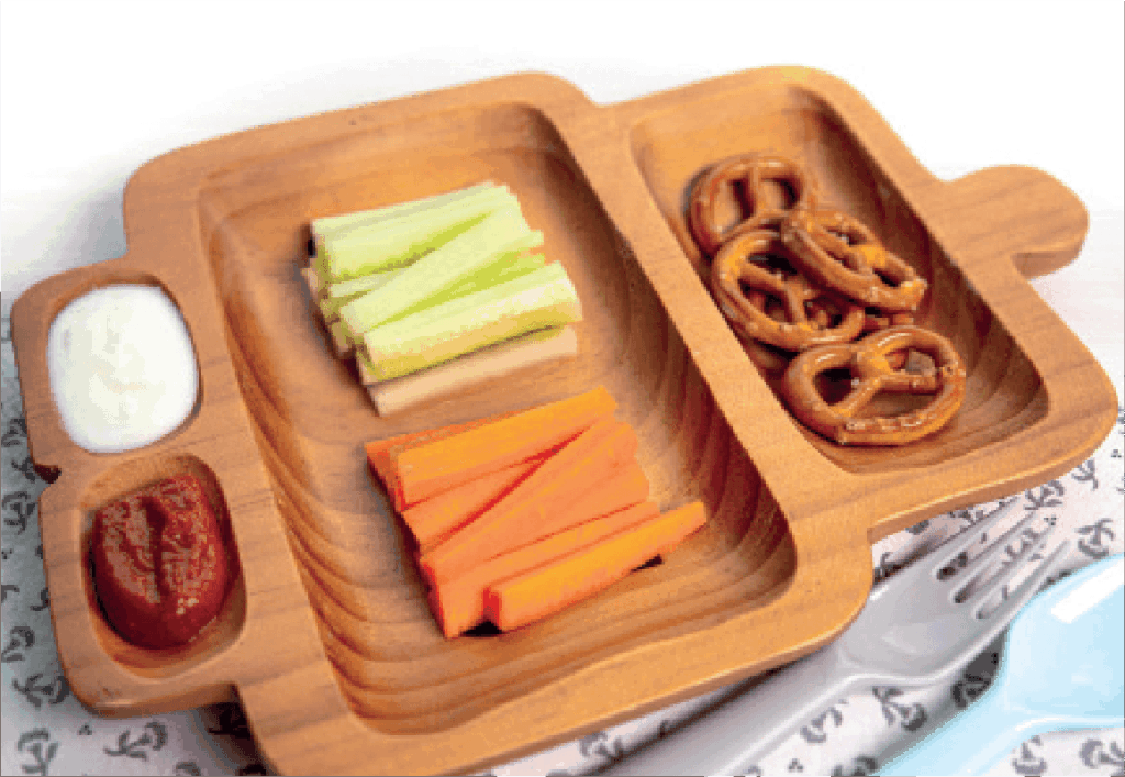 Carrot and cucumber sticks, pretzels, and two dips are served in a compartmentalized wooden tray.