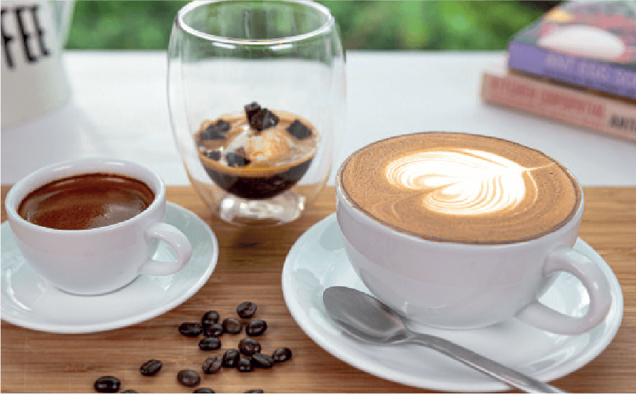 A coffee assortment including an espresso, an affogato, and a latte with heart-shaped art is presented on a wooden table with scattered coffee beans.